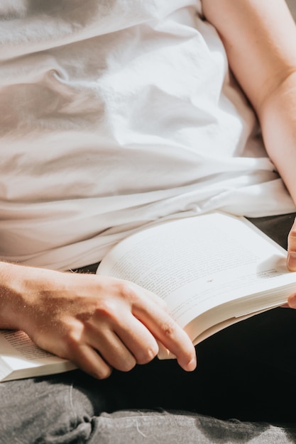 Super close-up van twee handen die een boek grijpen en lezen tijdens een super zonnige dag, ontspannen en geestelijke gezondheidsconcepten