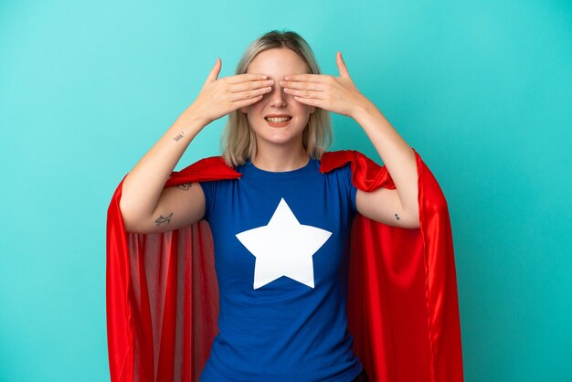 Super held blanke vrouw geïsoleerd op blauwe achtergrond die ogen bedekt door handen