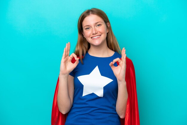 Super held blanke vrouw geïsoleerd op blauwe achtergrond met een ok teken met vingers
