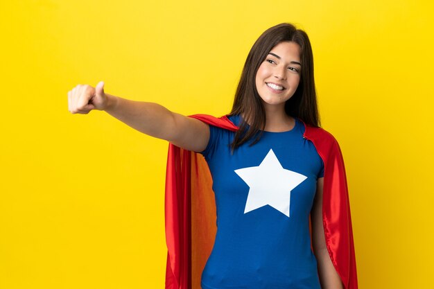 Super held Braziliaanse vrouw geïsoleerd op gele achtergrond met een duim omhoog gebaar