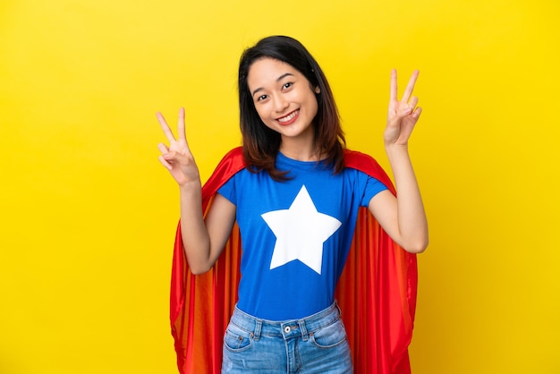 Super held Vietnamese vrouw geïsoleerd op gele achtergrond met overwinningsteken met beide handen