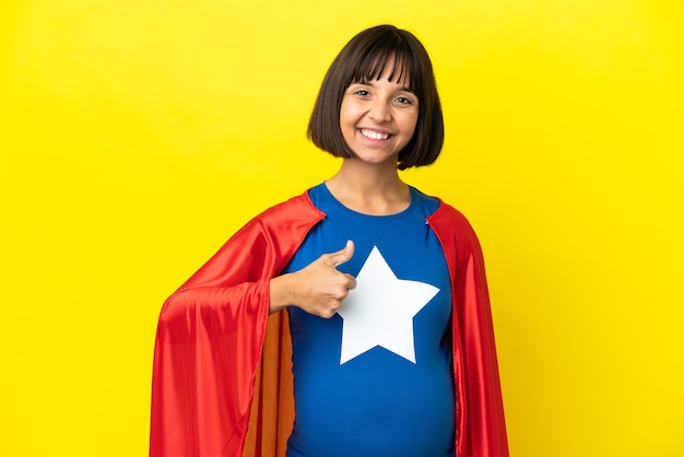 Super held zwangere vrouw geïsoleerd op gele achtergrond met een duim omhoog gebaar