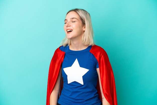 Super Hero blanke vrouw geïsoleerd op blauwe achtergrond lachen in laterale positie