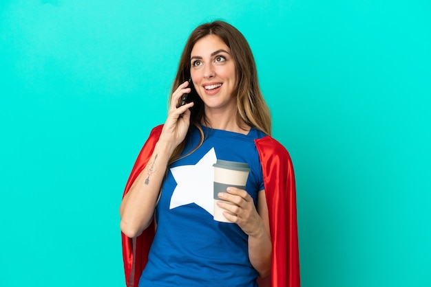 Super Hero blanke vrouw geïsoleerd op blauwe achtergrond met koffie om mee te nemen en een mobiel