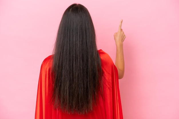 Super Hero blanke vrouw geïsoleerd op roze achtergrond wijzend terug met de wijsvinger