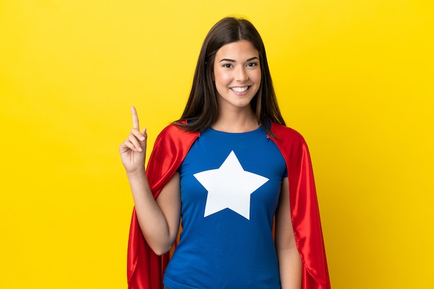 Super Hero Braziliaanse vrouw geïsoleerd op een gele achtergrond die een vinger toont en opheft in teken van de beste