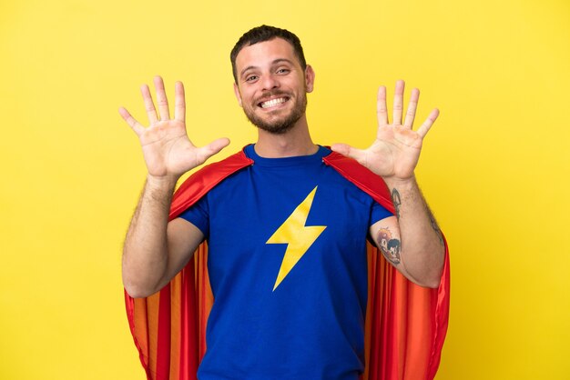 Super Hero Brazilian man isolated on yellow background counting ten with fingers