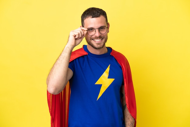 Бразильский человек супергероя изолирован на желтом фоне в очках и счастлив