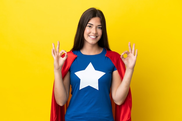 Super Hero Brazilian woman isolated on yellow background showing an ok sign with fingers