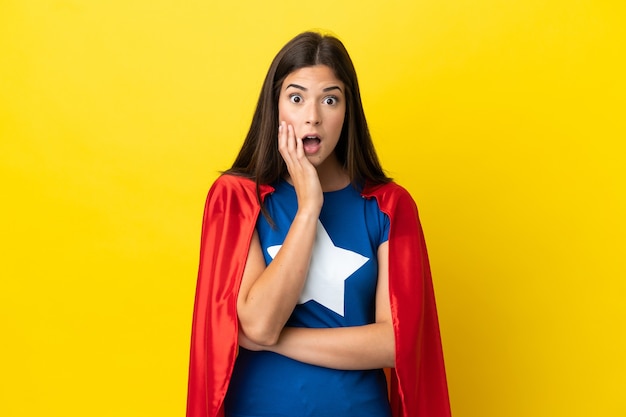 Super Hero Brazilian woman isolated on yellow background surprised and shocked while looking right