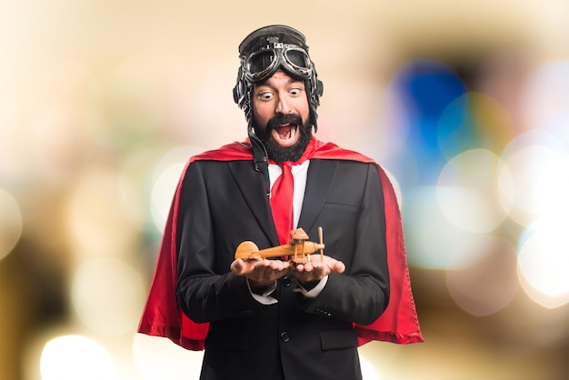 Super hero businessman holding a wooden toy airplane on unfocused background