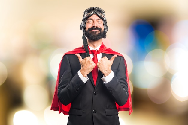 Super hero businessman with thumb up on unfocused background