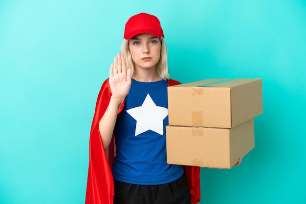 Super hero caucasian delivery woman isolated on blue background\
making stop gesture