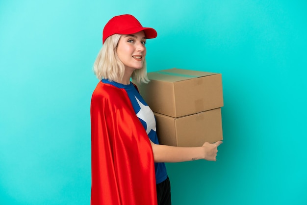 Super Hero caucasian delivery woman isolated on blue background pointing back