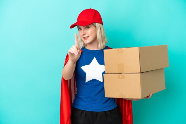 Donna di consegna caucasica super hero isolata su sfondo blu che mostra e solleva un dito