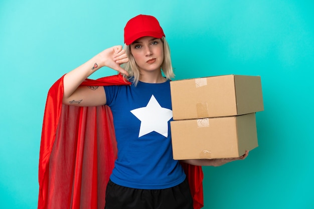 Super Hero caucasian delivery woman isolated on blue background showing thumb down with negative expression