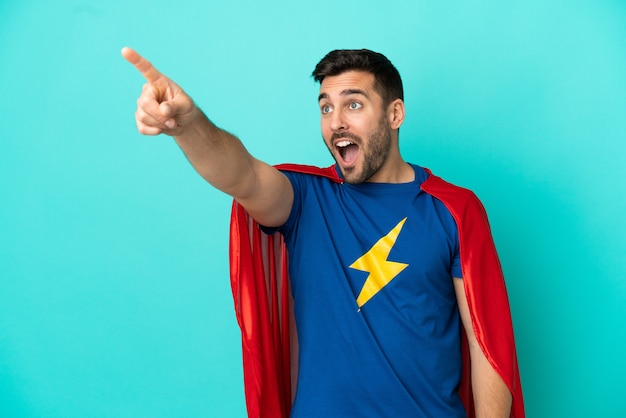 Super Hero caucasian man isolated on blue background pointing away