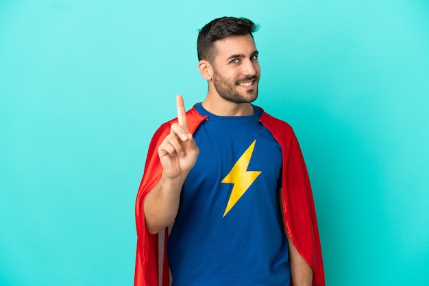 Super Hero caucasian man isolated on blue background showing and lifting a finger