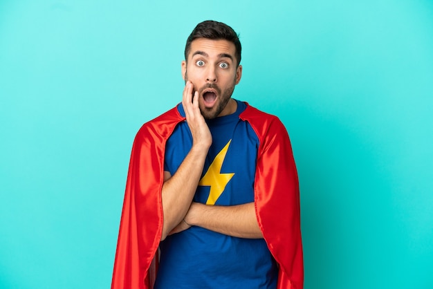 Super hero caucasian man isolated on blue background surprised and shocked while looking right