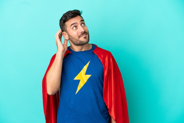 Super Hero caucasian man isolated on blue background thinking an idea