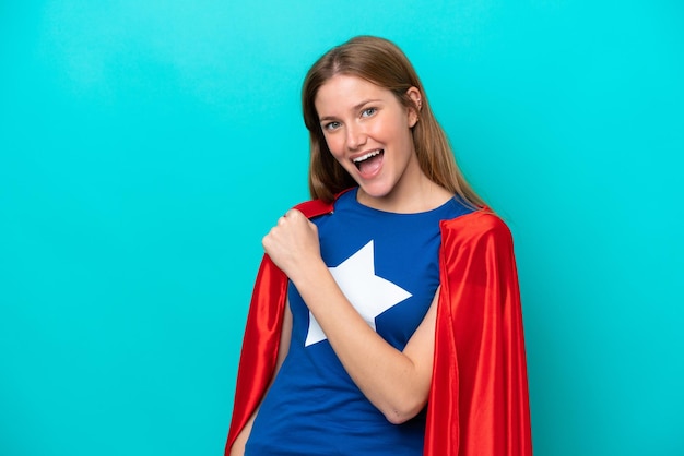 Super Hero caucasian woman isolated on blue background celebrating a victory