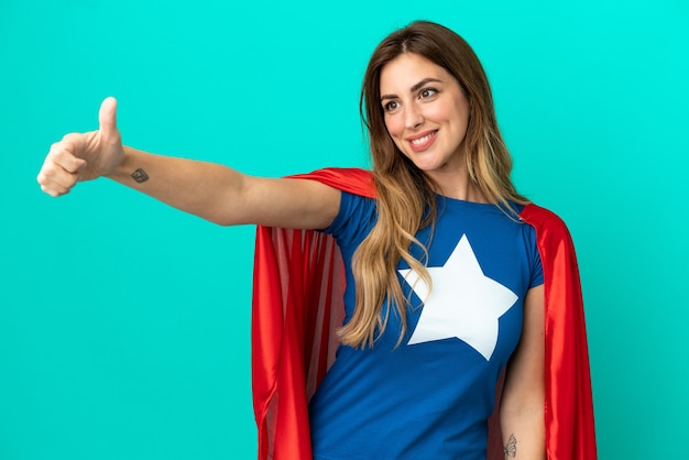 Super Hero caucasian woman isolated on blue background giving a thumbs up gesture