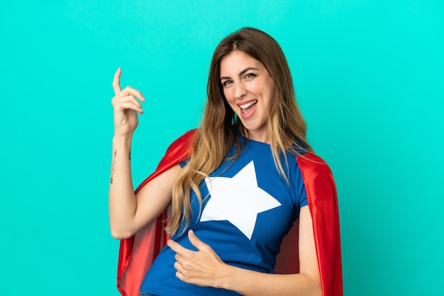 Super Hero caucasian woman isolated on blue background making guitar gesture