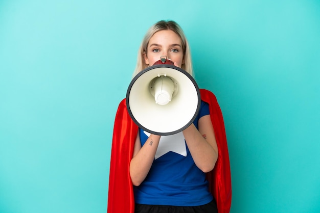 Super Hero caucasian woman isolated on blue background shouting through a megaphone