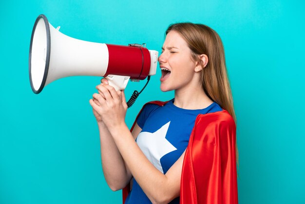 Super Hero caucasian woman isolated on blue background shouting through a megaphone