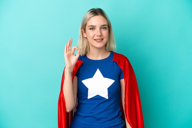 손가락으로 확인 표시를 보여주는 파란색 배경에 고립 된 슈퍼 영웅 백인 여자