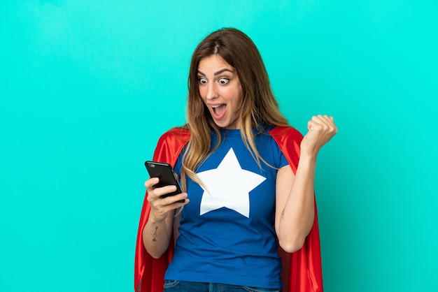 Super Hero caucasian woman isolated on blue background surprised and sending a message