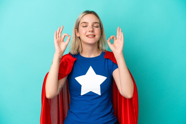 Super Hero caucasian woman isolated on blue background in zen pose