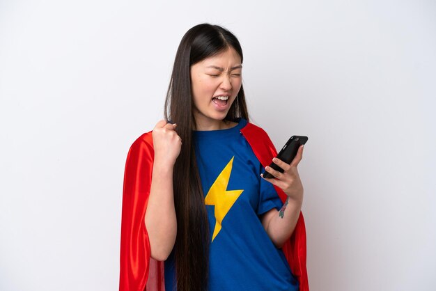 Китаянка-супергерой изолирована на белом фоне с телефоном в победной позиции