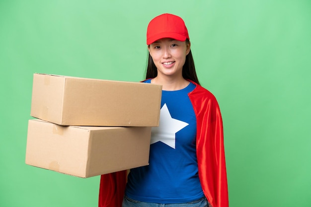 Super Hero delivery Asian woman holding boxes over isolated background looking side