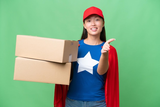 Super Hero delivery Asian woman holding boxes over isolated background shaking hands for closing a good deal