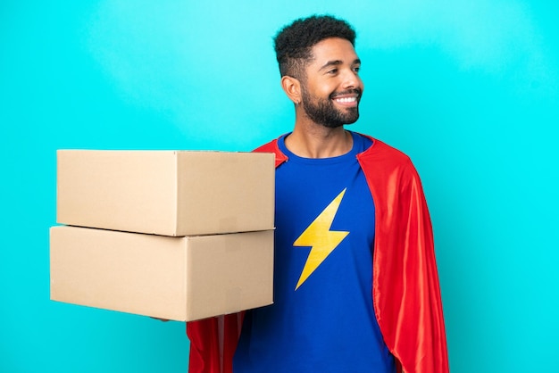 Super Hero delivery Brazilian man isolated on blue background looking side