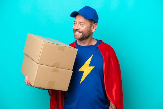 Super Hero delivery man isolated on blue background looking to the side and smiling