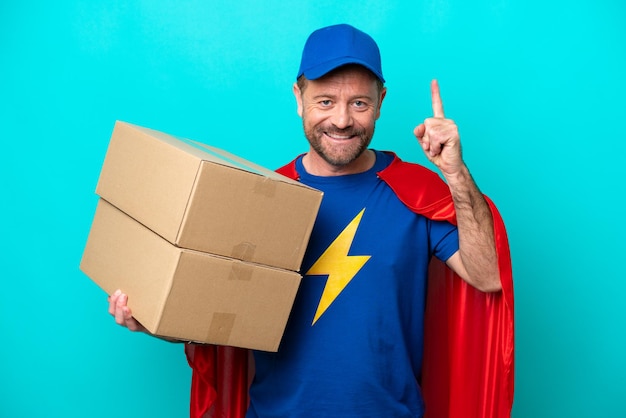 Photo super hero delivery man isolated on blue background pointing up a great idea