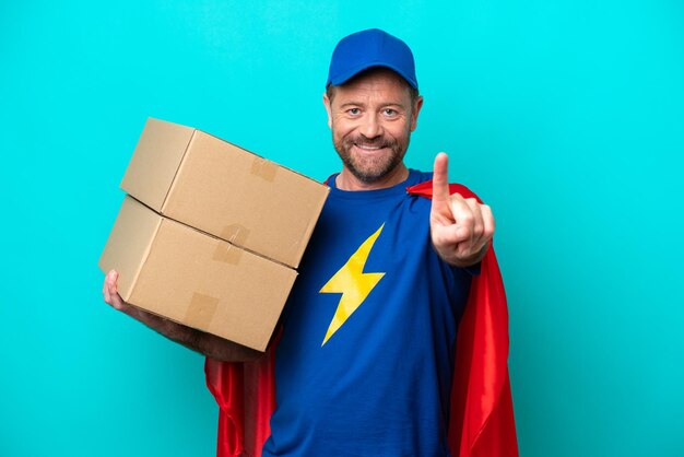 Photo super hero delivery man isolated on blue background showing and lifting a finger