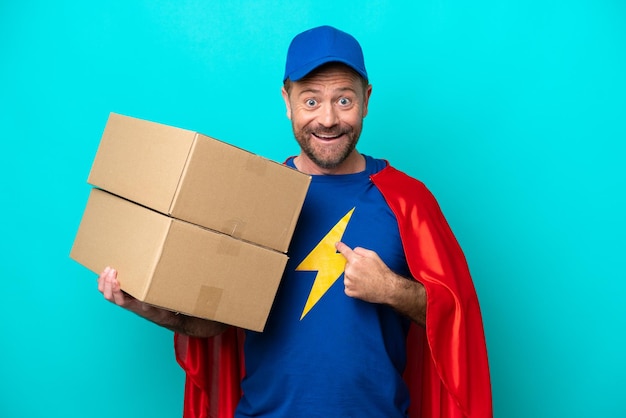 Super Hero delivery man isolated on blue background with surprise facial expression