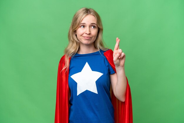 Photo super hero english woman over isolated background with fingers crossing and wishing the best