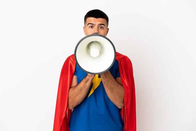 Super Hero over isolated white wall shouting through a megaphone