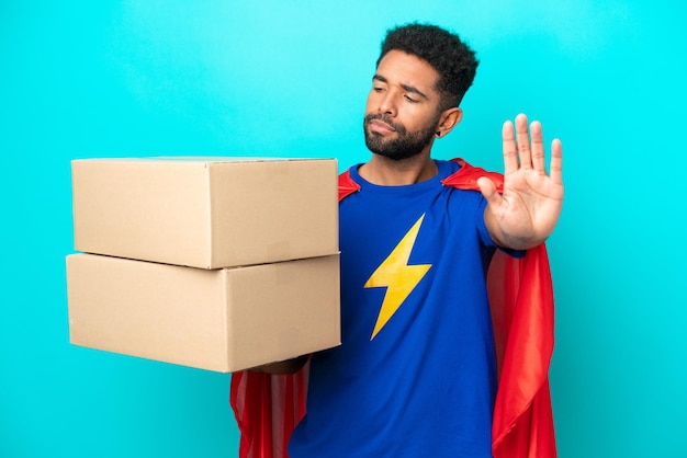 Super Hero levering Braziliaanse man geïsoleerd op blauwe achtergrond stop gebaar maken en teleurgesteld