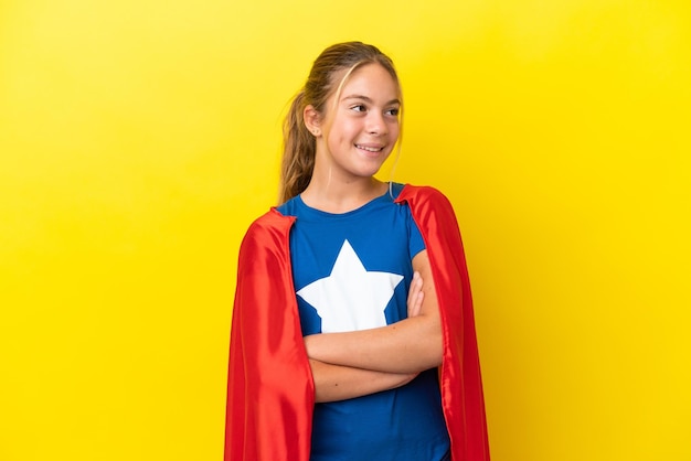 Super hero little girl isolated on yellow background happy and\
smiling