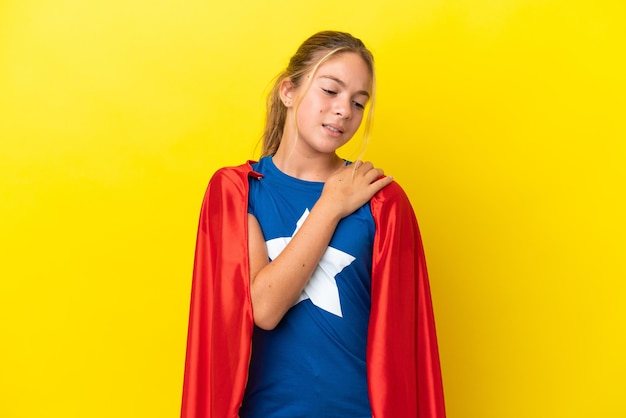 Super hero little girl isolated on yellow background suffering\
from pain in shoulder for having made an effort