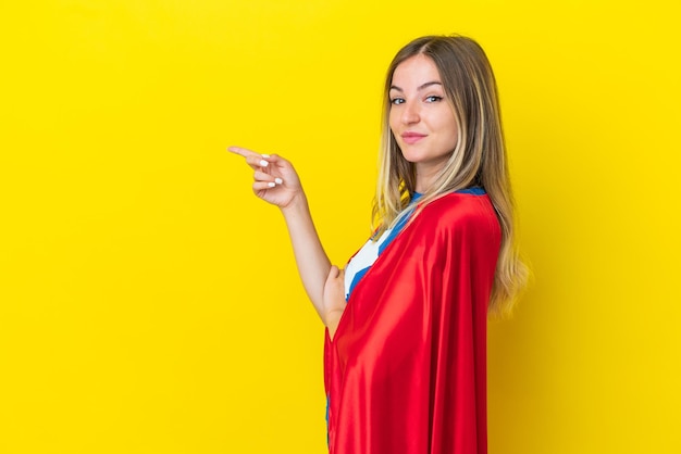 Super Hero Roemeense vrouw geïsoleerd op gele achtergrond wijzende vinger naar de zijkant