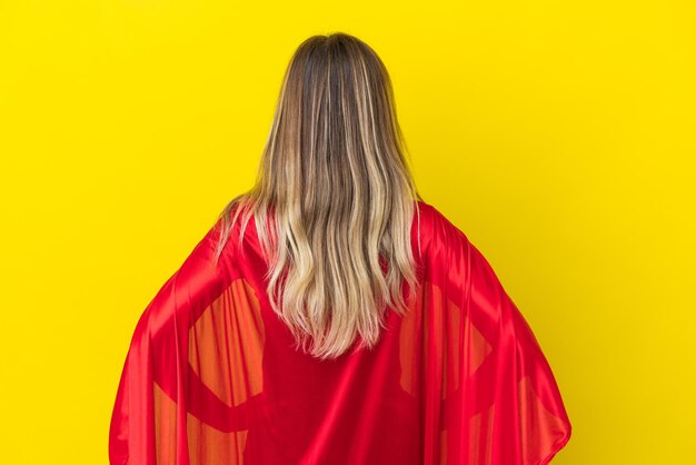 Super Hero Romanian woman isolated on yellow background in back position