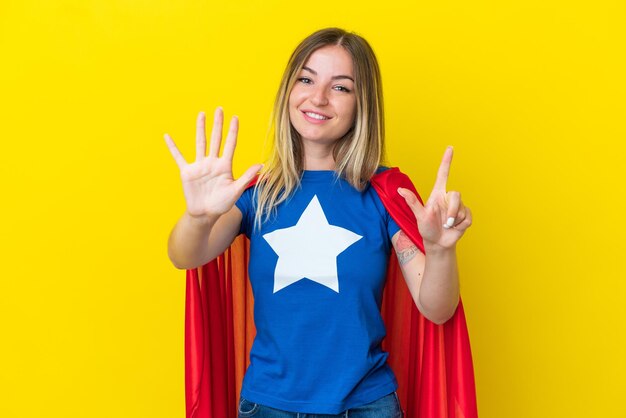 Super hero romanian woman isolated on yellow background\
counting seven with fingers