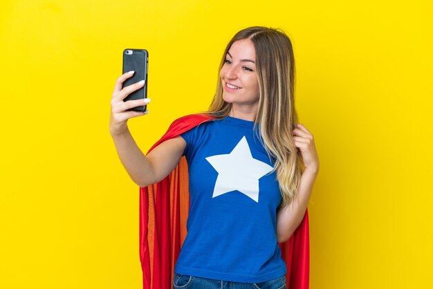 Super hero romanian woman isolated on yellow background making a selfie