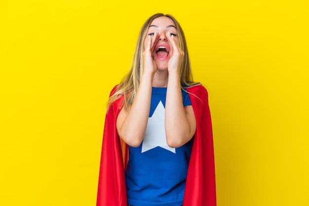 Super hero romanian woman isolated on yellow background\
shouting and announcing something